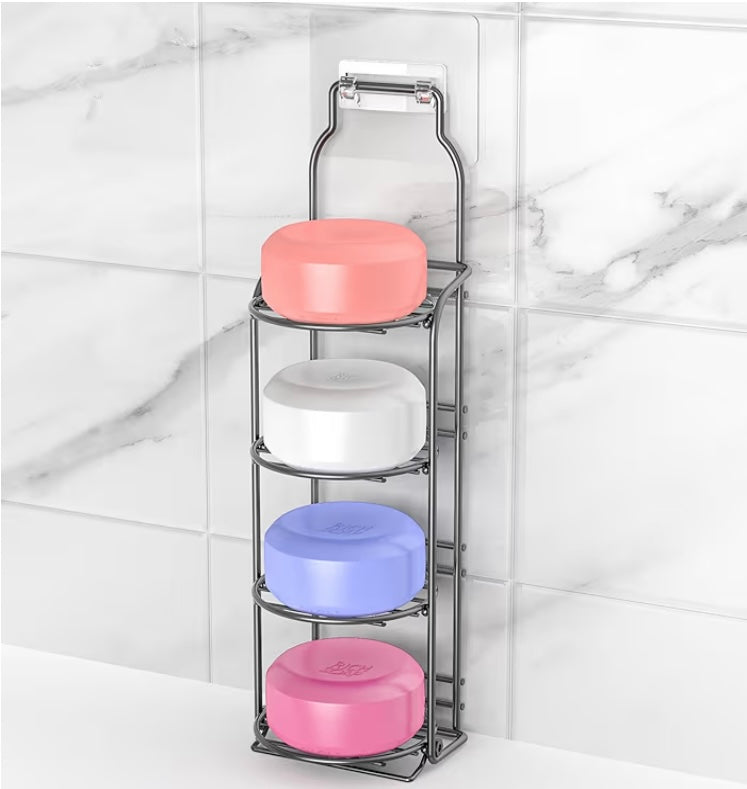 Four-tier metal soap holder with colorful soap bars against a marble bathroom wall.