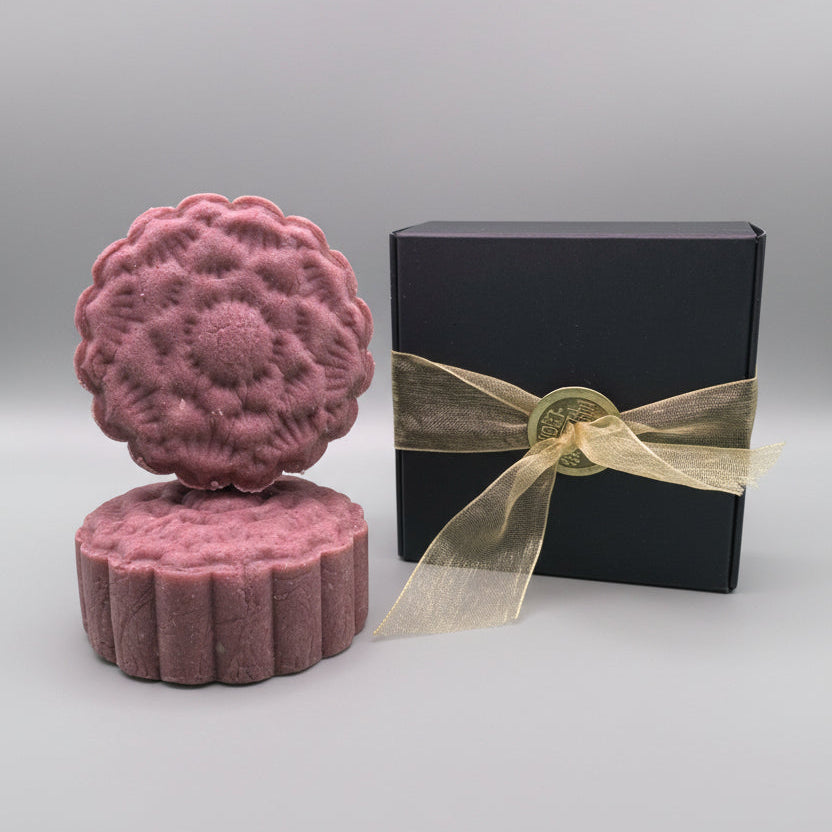 Purple shampoo bar sitting next to a black box with gold ribbon