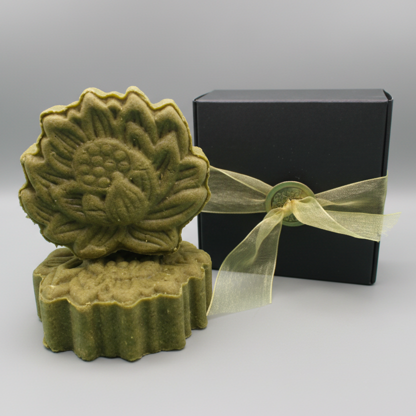 Green hemp shampoo bar sitting next to a black box with gold ribbon