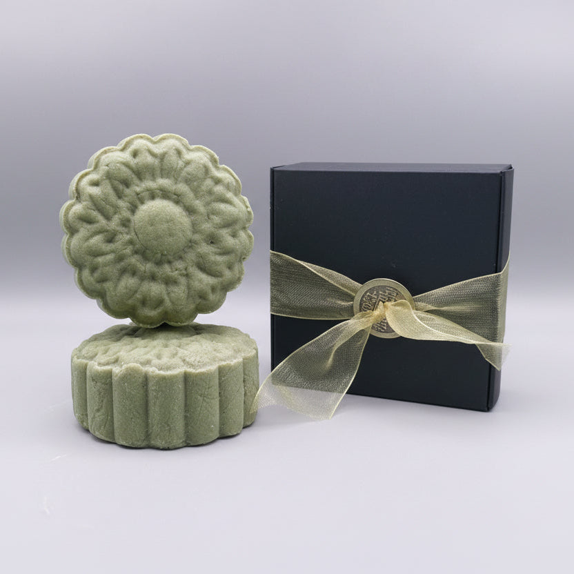 Honey Revive Shampoo Bar sitting next to a black box with gold ribbon
